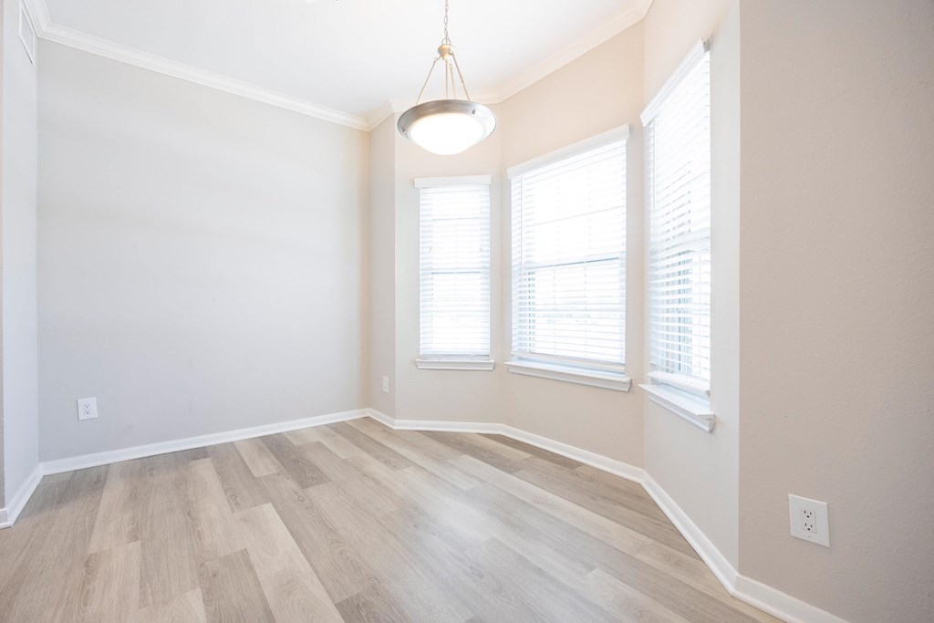 an empty living room with wood flooring and three windows