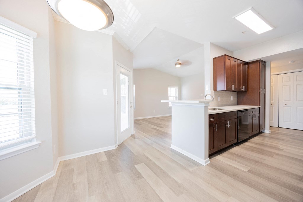 a renovated kitchen and living room with white walls and wood floors