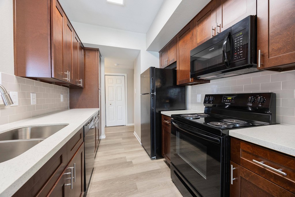 a kitchen with black appliances and wooden cabinets and white counter tops