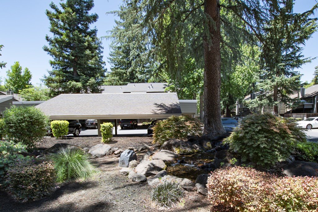 A house with a grey roof is surrounded by trees and plants.