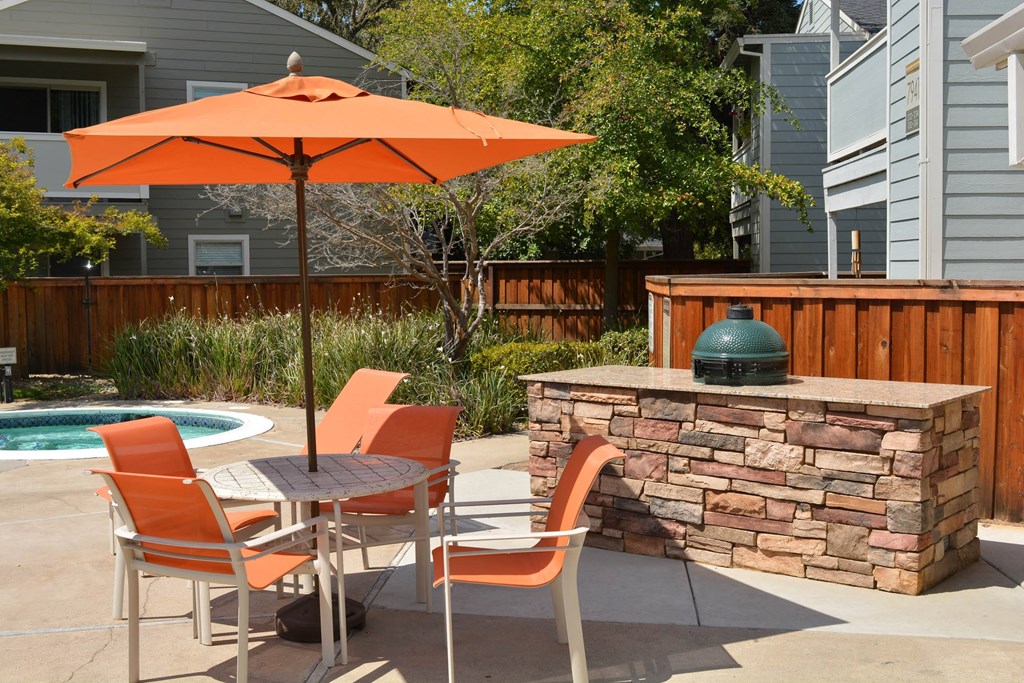 View of pool spa and grill area with orange umbrellas and seating area