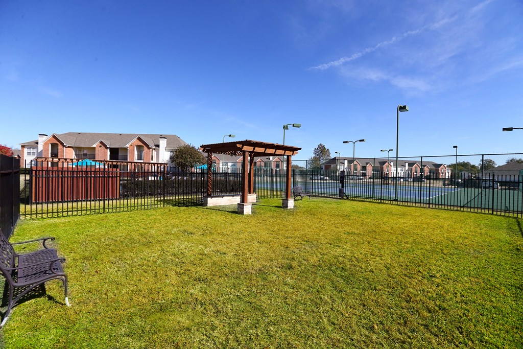 View of fenced dog park with pergola and sitting area