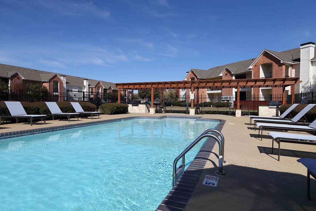 View of second pool on property with ample lounging chairs, sitting areas, and grilling station with two grills and counter space to prepare food.
