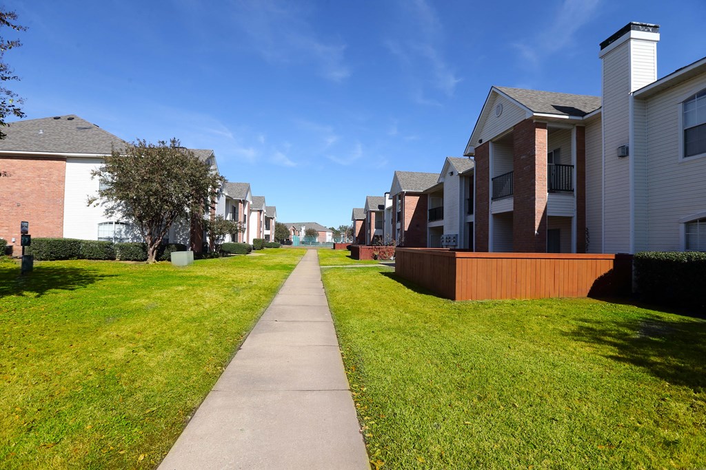 View of private patio with fenced in yard, lush landscaping, and side walk winding in between