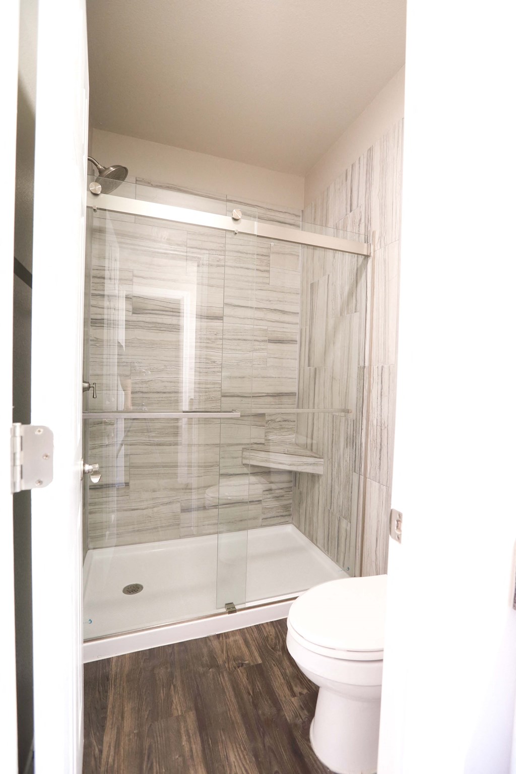View of walk in shower with tiled wall and toilet