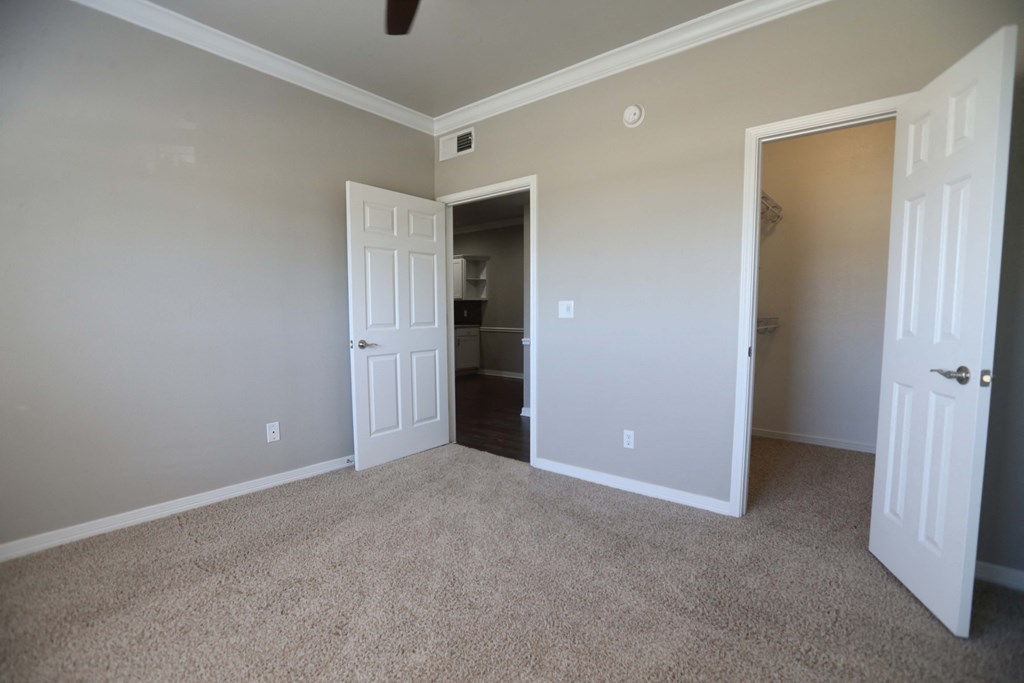 View of bedroom with a peak into the walk in closet and view from bedroom into the dining area