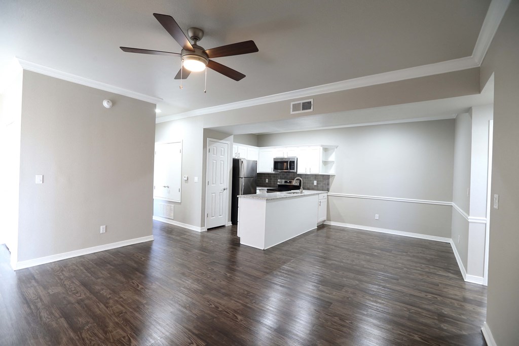 huge living area with dark wooden floors and white walls