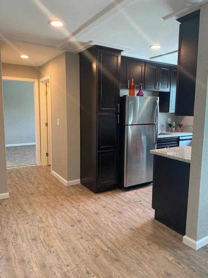 Kitchen and hallway view, featuring brown cabinets, stainless appliances, wood like flooring
