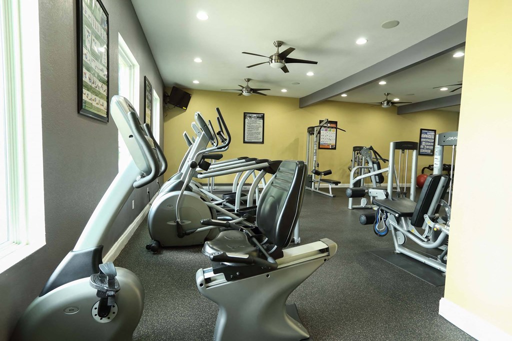 A gym with a variety of equipment including treadmills, stationary bikes, and weight machines at Willow Creek Apartments, Houston, TX