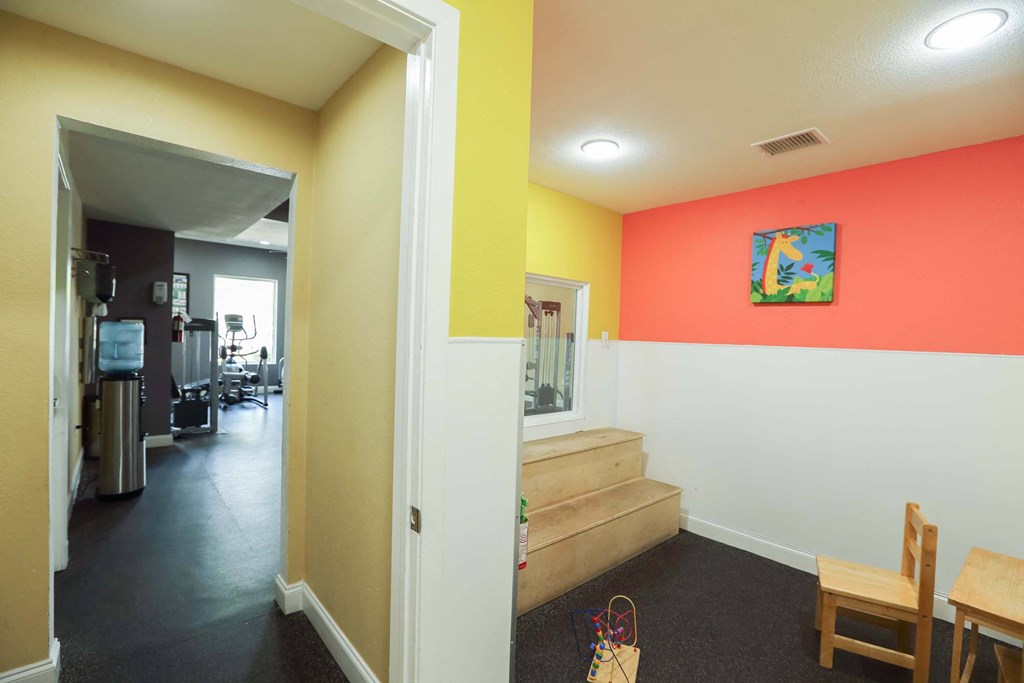 A hallway with a chair and a table in the foreground and a room with a painting on the wall in the background at Willow Creek Apartments, Texas, 77012