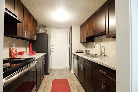 A kitchen with a black refrigerator and brown cabinets.