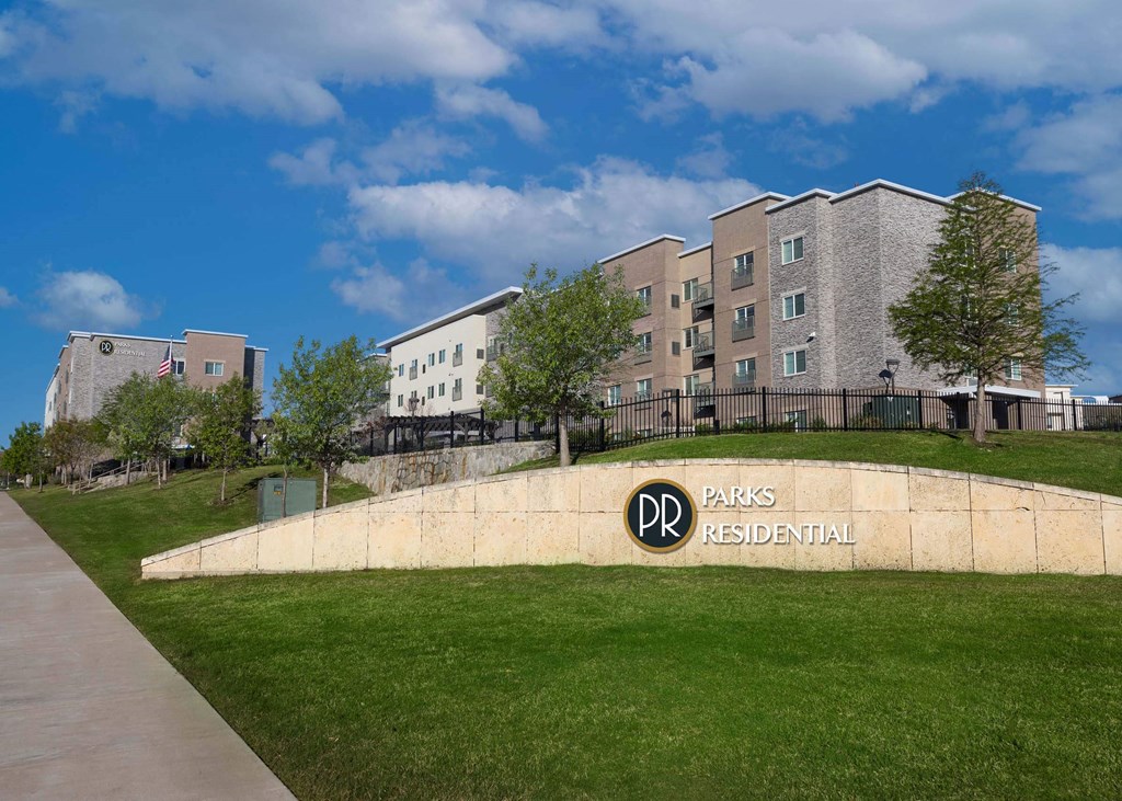 a building with a park and a sign in front of it  at Parks Residential - Richardson, Richardson, 75082