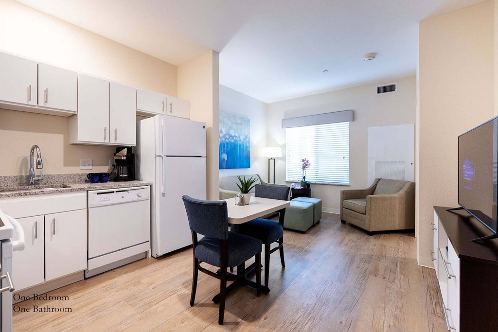 a kitchen and living room with white appliances and wood floors at Parks Residential - Richardson, Richardson, Texas