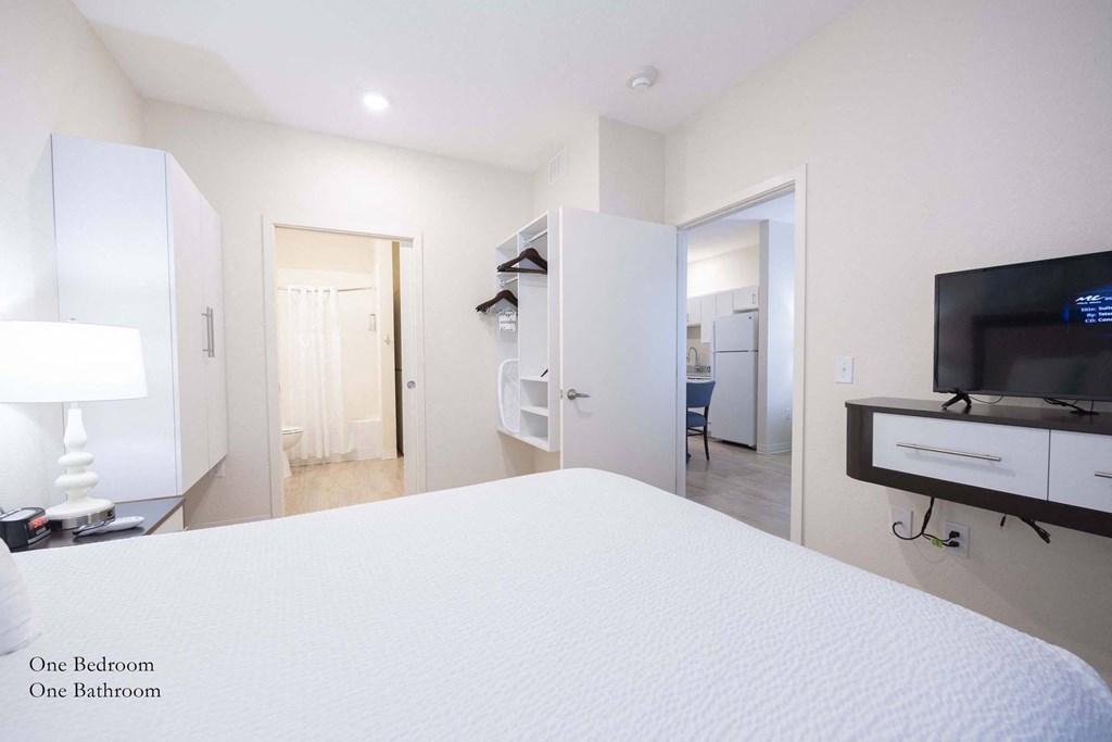 a bedroom with a large white bed and a tv  at Parks Residential - Richardson, Richardson, 75082