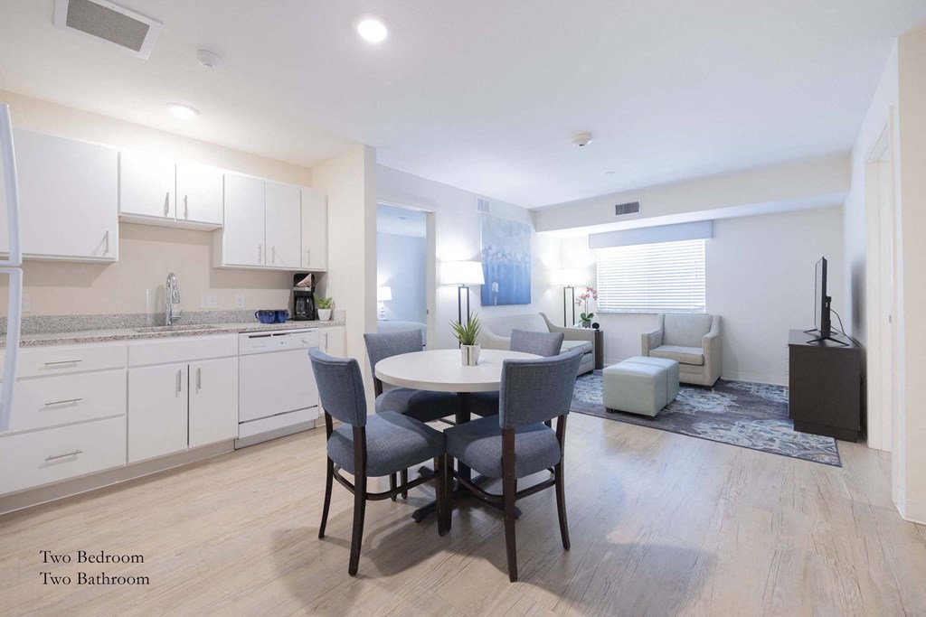 a kitchen and living room with white cabinets and a table and chairs at Parks Residential - Richardson, Texas