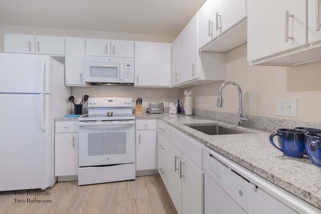 a white kitchen with white appliances and white cabinets at Parks Residential - Richardson, Richardson, Texas