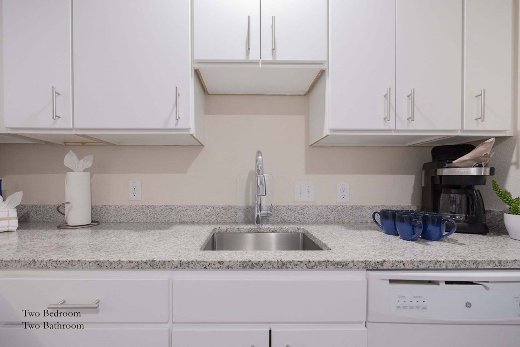 a kitchen counter with a sink and white cabinets at Parks Residential - Richardson, Texas, 75082