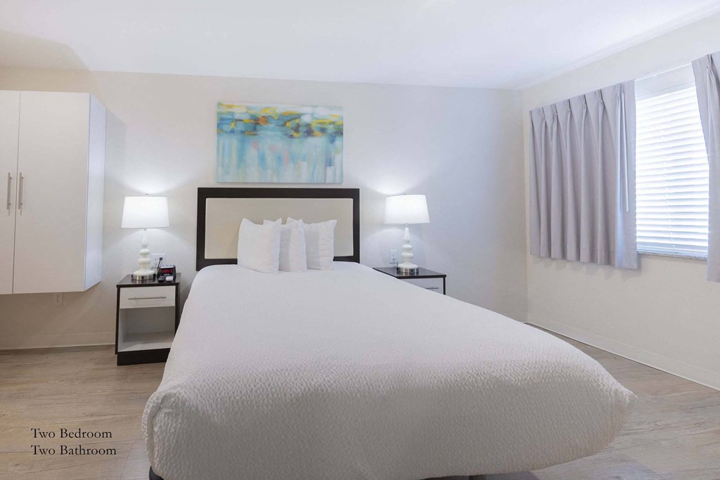 a bedroom with a bed and two nightstands and a window  at Parks Residential - Richardson, Texas