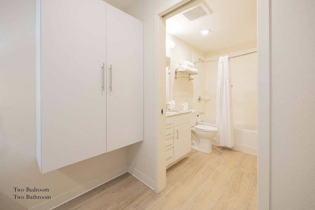 a bathroom with white cabinets and a toilet and a sink at Parks Residential - Richardson, Richardson, Texas
