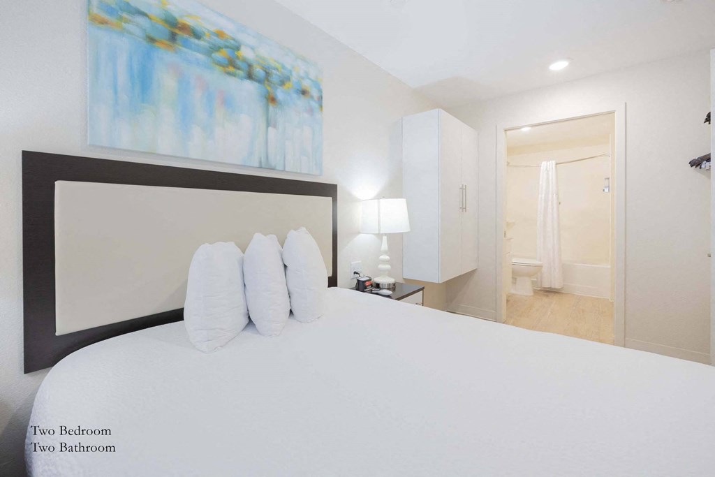 a bedroom with a large white bed and a painting on the wall at Parks Residential - Richardson, Texas, 75082