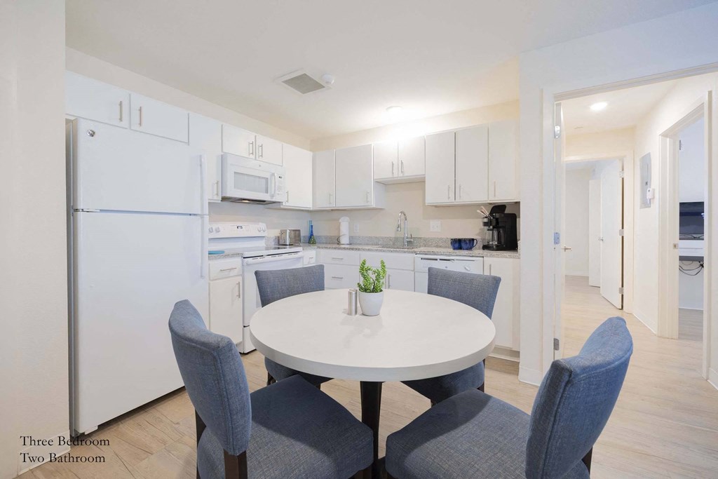 a kitchen with white cabinets and a white table and chairs at Parks Residential - Richardson, Richardson, TX, 75082