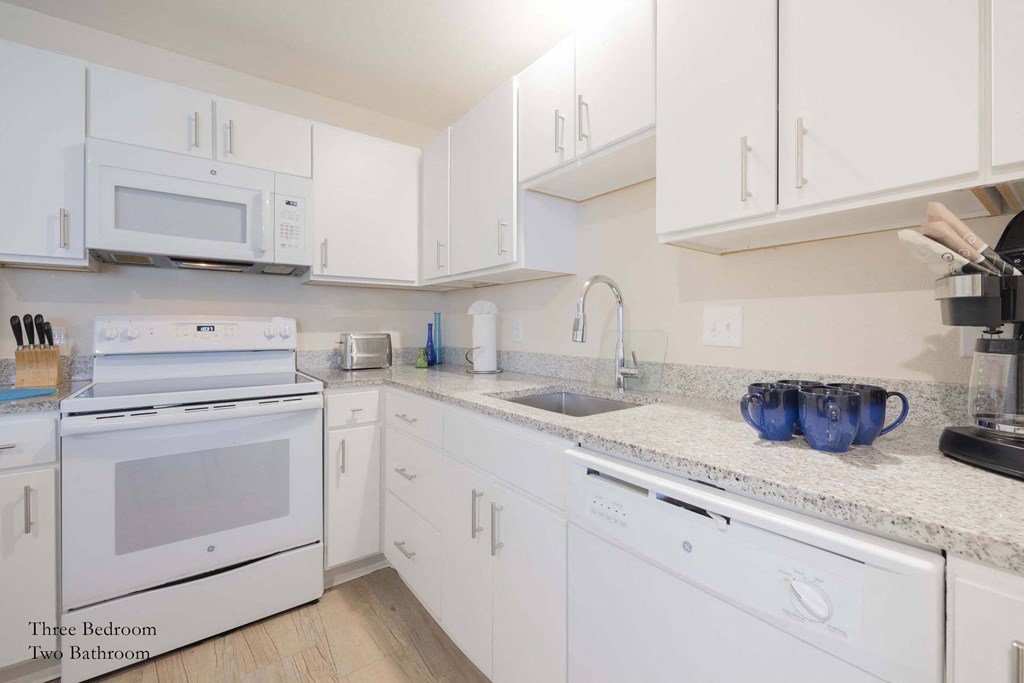 a white kitchen with white appliances and white cabinets at Parks Residential - Richardson, Texas