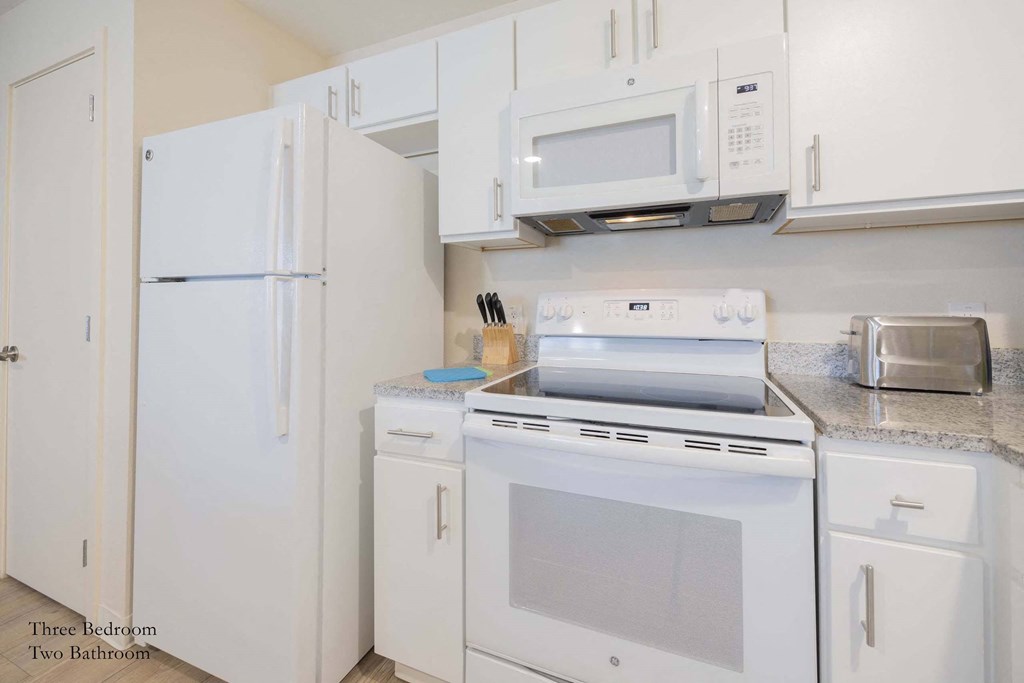 a kitchen with white appliances and white cabinets at Parks Residential - Richardson, Richardson, TX, 75082