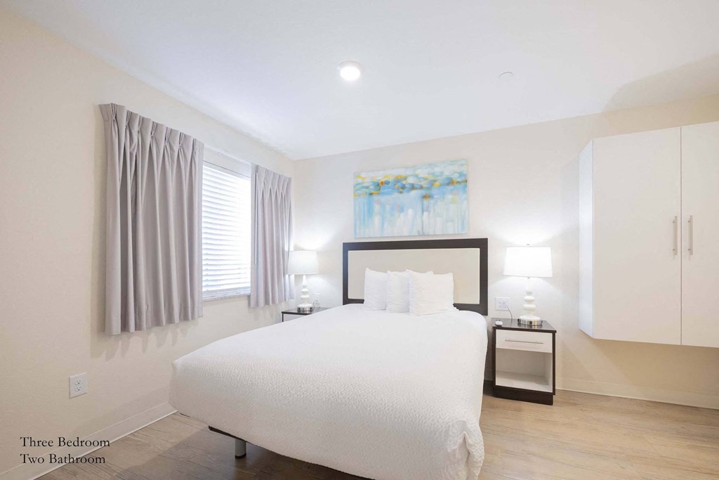 a white bedroom with a large white bed and white cabinets at Parks Residential - Richardson, Richardson, 75082