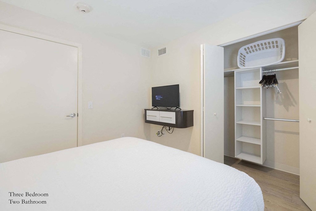 a bedroom with a bed and a closet and a television at Parks Residential - Richardson, Richardson, 75082