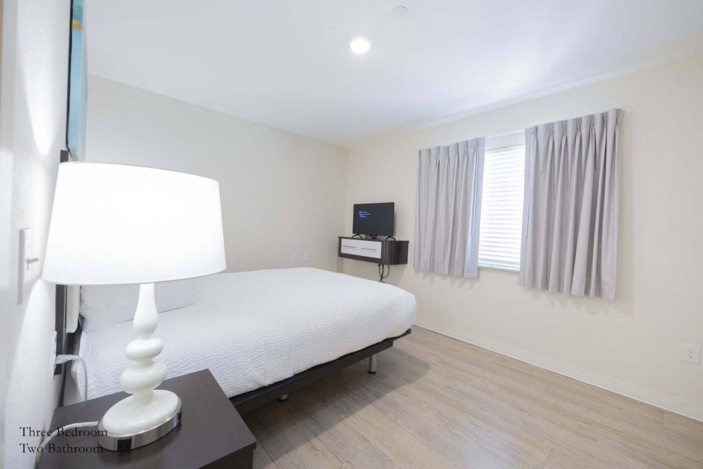 a bedroom with a bed and a lamp and a window at Parks Residential - Richardson, Richardson, Texas