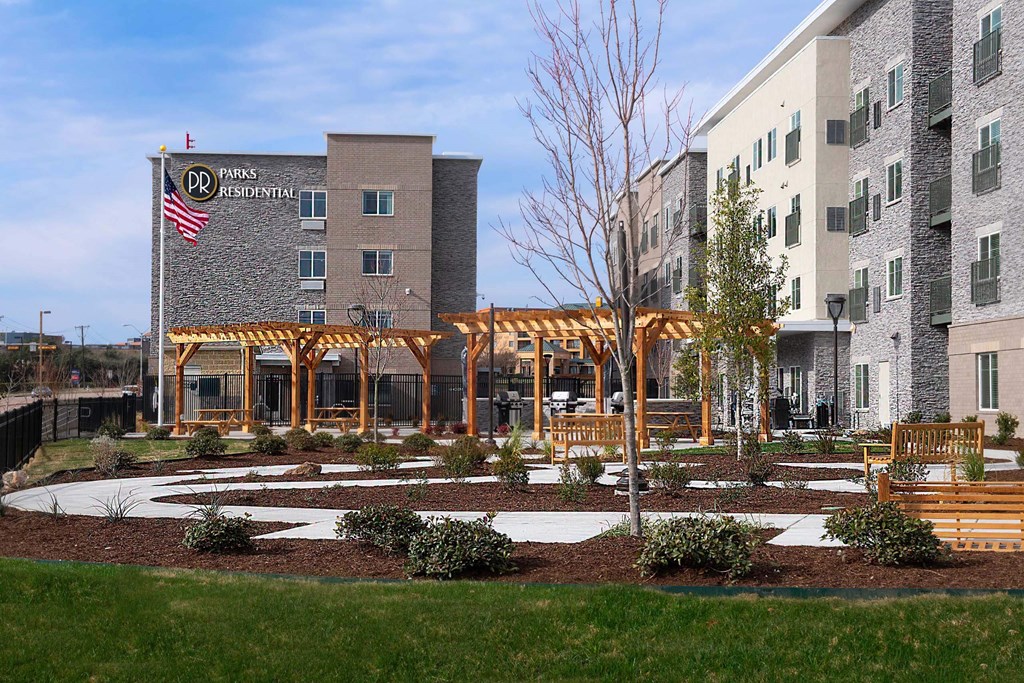 a courtyard with benches and a building with an flag  at Parks Residential - Richardson, Texas