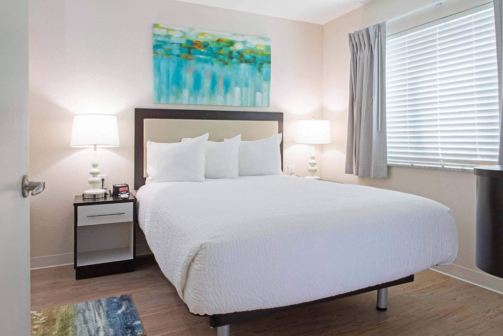 a bedroom with a white bed and a painting on the wall at Parks Residential - Denver, Colorado, 80111