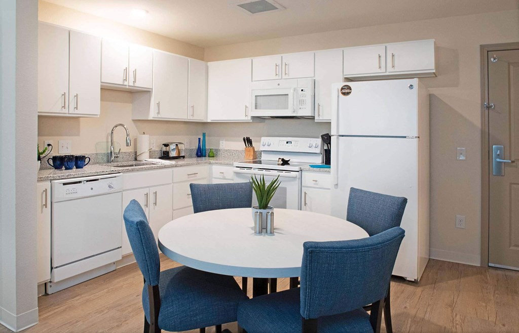 a kitchen with white appliances and a white table and chairs at Parks Residential - Denver, Centennial