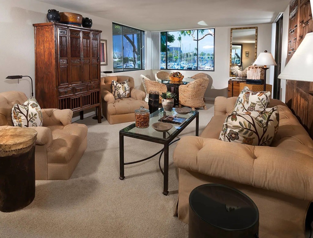 A living room with a glass coffee table and a large window.
