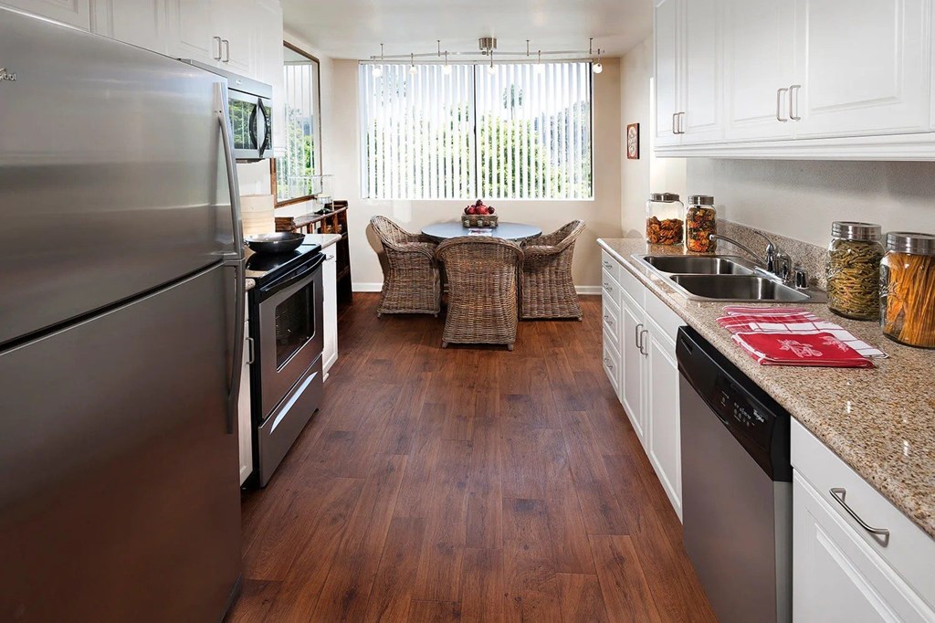 A kitchen with a refrigerator on the left and a dining table in the middle.