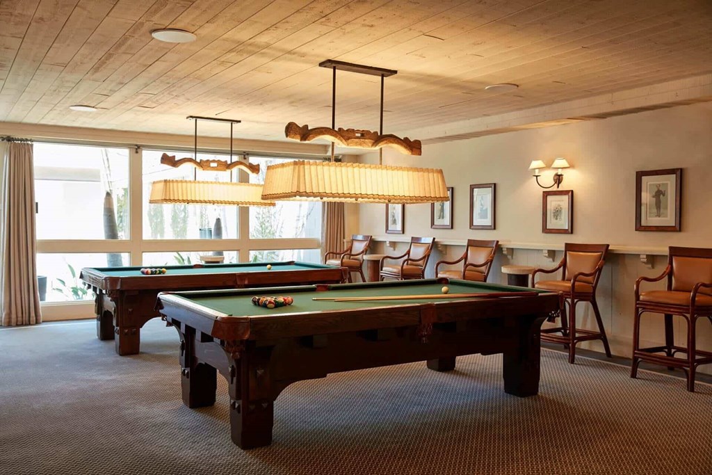 A room with a pool table and chairs.