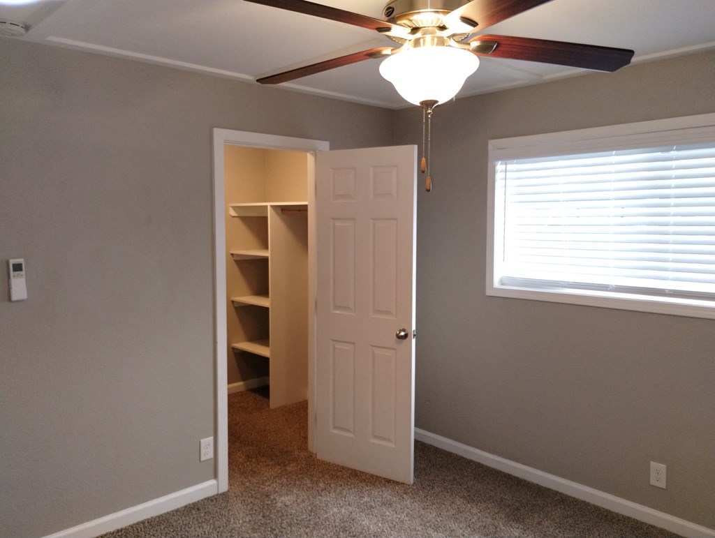 a bedroom with a ceiling fan and a closet