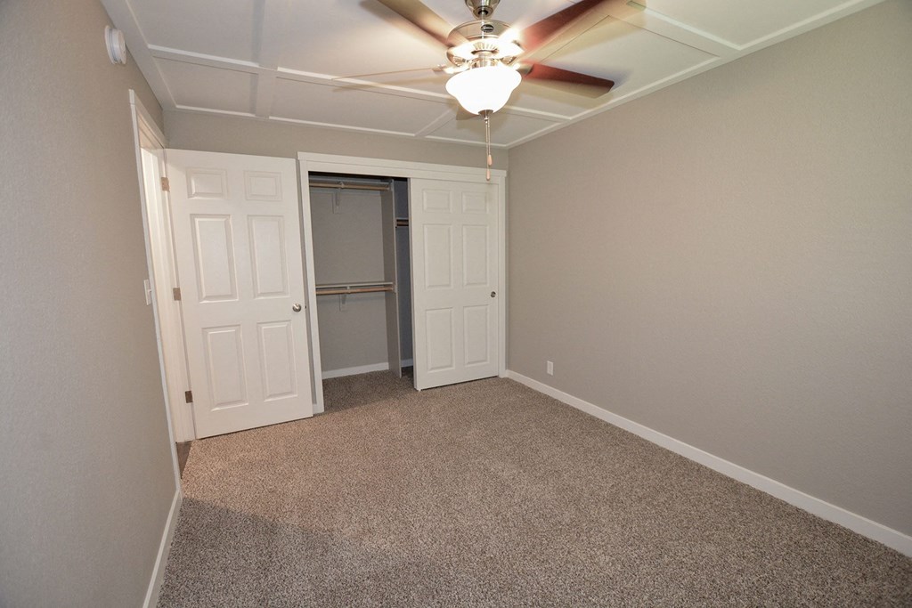 View of bedroom with carpet flooring, ceiling fan, sliding door access to closet