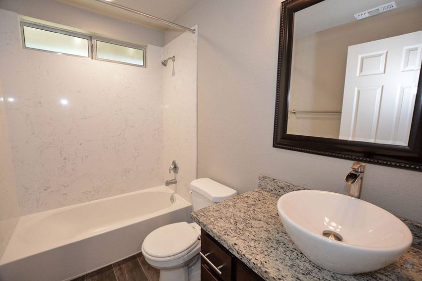 Bathroom view of bathroom with vessel sink, mirror, toilet, tub shower combo, and well lit window - Photo Gallery