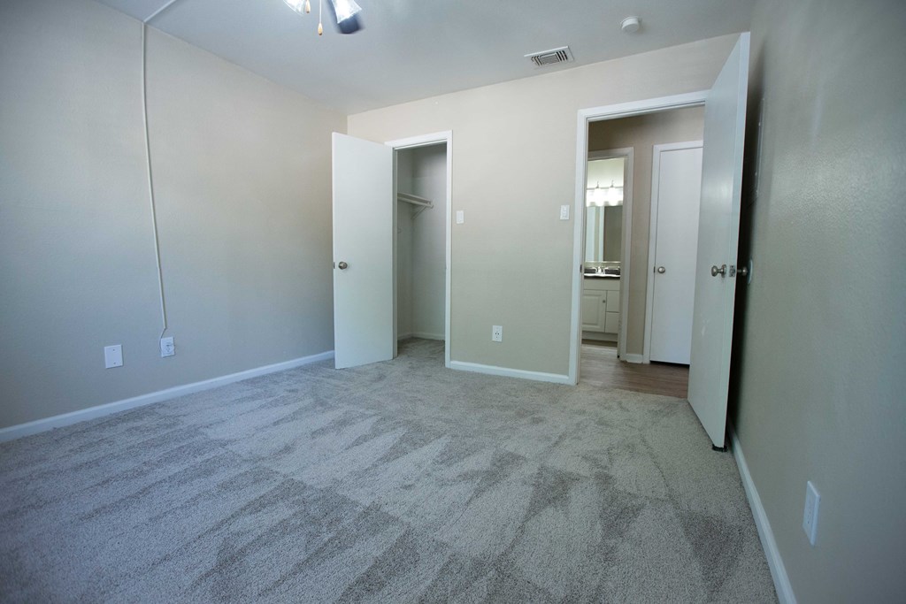 Rolling Brook Bedroom with carpet flooring, view into walk in closet and view into bathroom