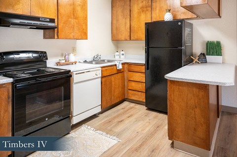 A kitchen with a black refrigerator and wooden cabinets.