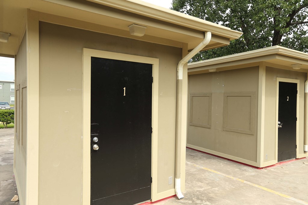 the outside of a garage with a black door and two garage doors