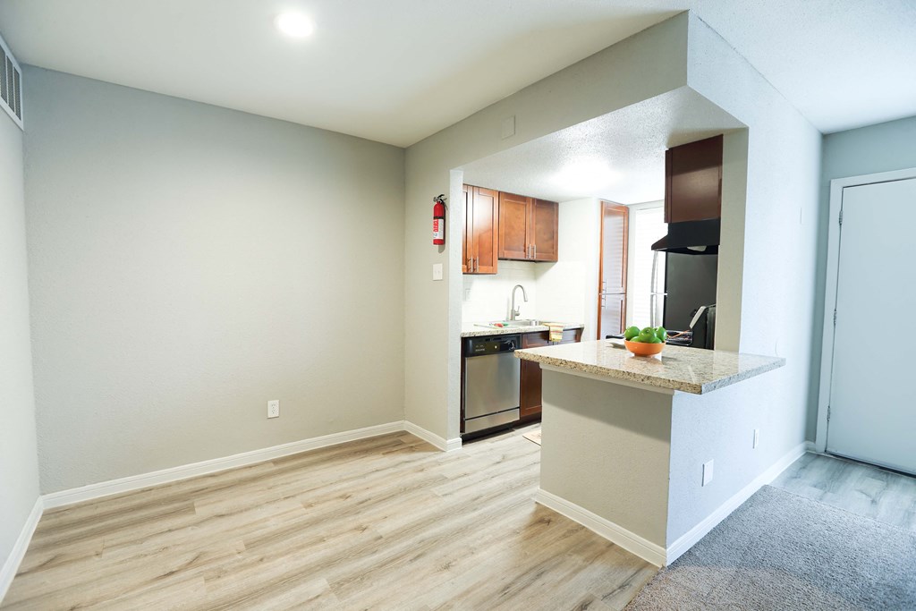 an empty living room with a kitchen with a counter top