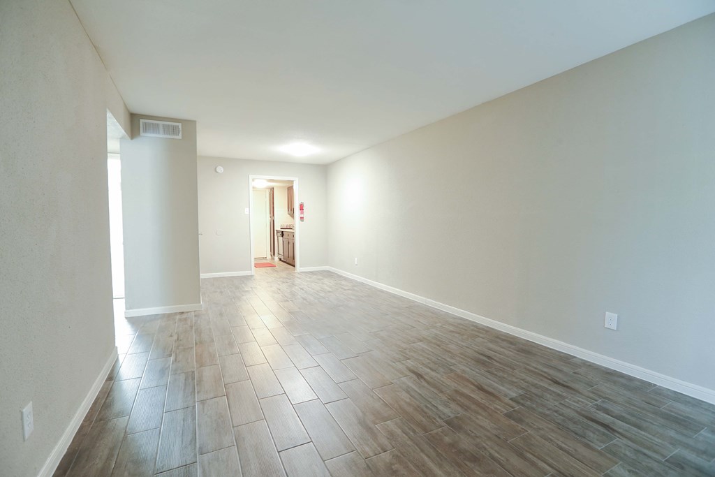 the living room and dining room of an empty house with wood flooring