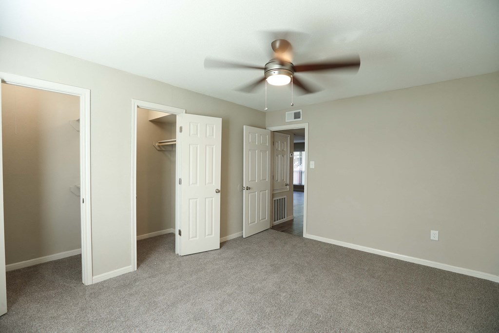 an empty living room with a ceiling fan and a closet