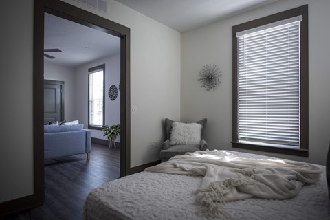 A bedroom with a bed covered in a white blanket and a mirror on the wall.