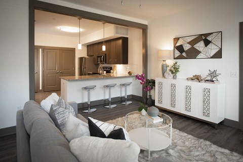 A modern living room with a grey sofa and a glass coffee table.