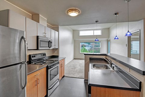 A kitchen with a stainless steel refrigerator, microwave, oven, and sink.