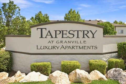 A sign for Tapestry at Granville Luxury Apartments is displayed in front of a building.