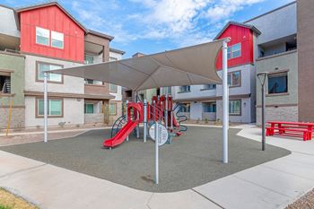 A playground with a red slide and a grey canopy.